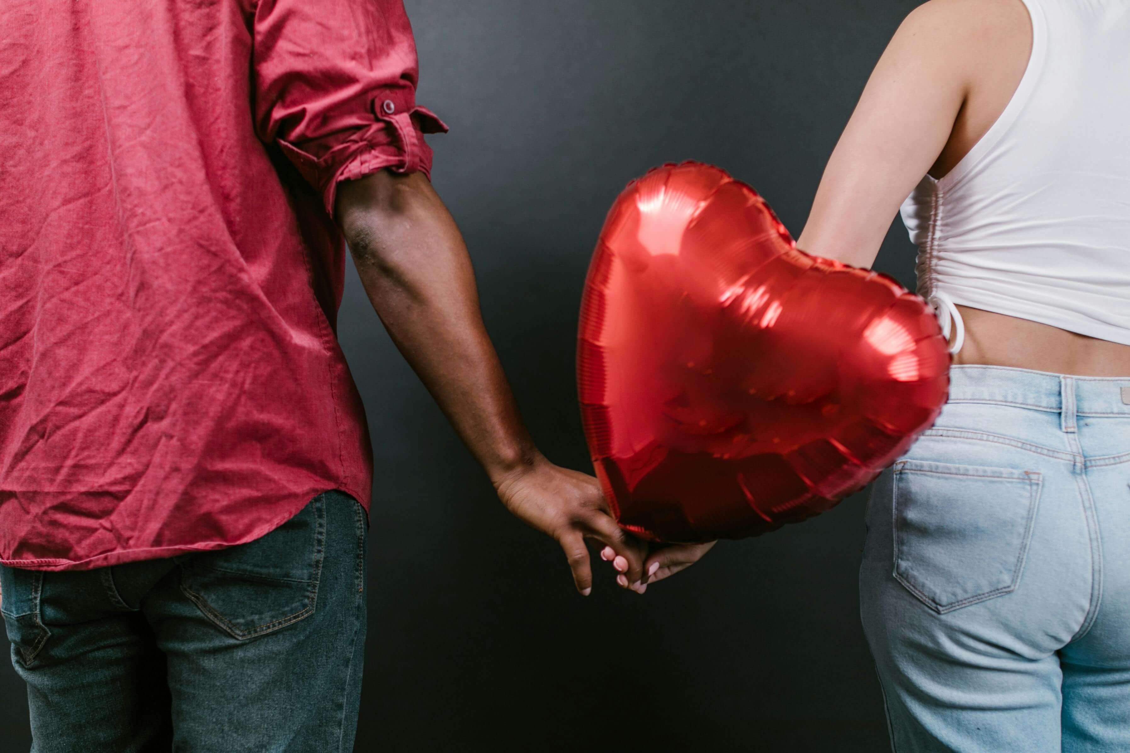 a couple holding a red love heart balloon