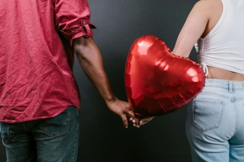 a couple holding a red love heart balloon