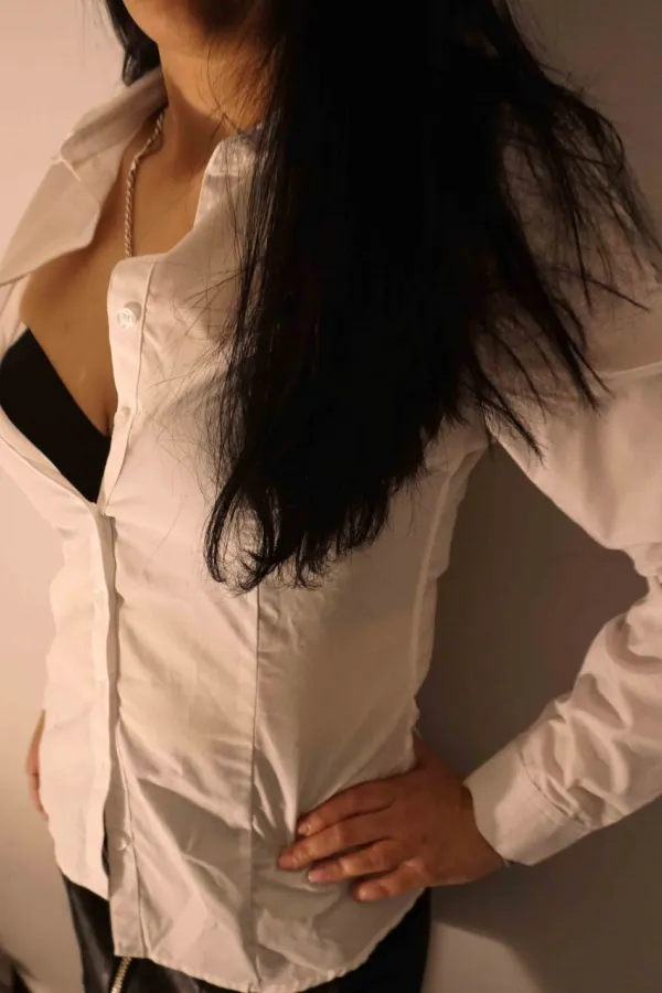 Hanna wearing a white shirt with a black bra